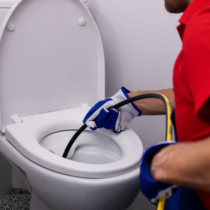 Technicien LD Suisse passant un furet mécanique dans une toilette bouchée